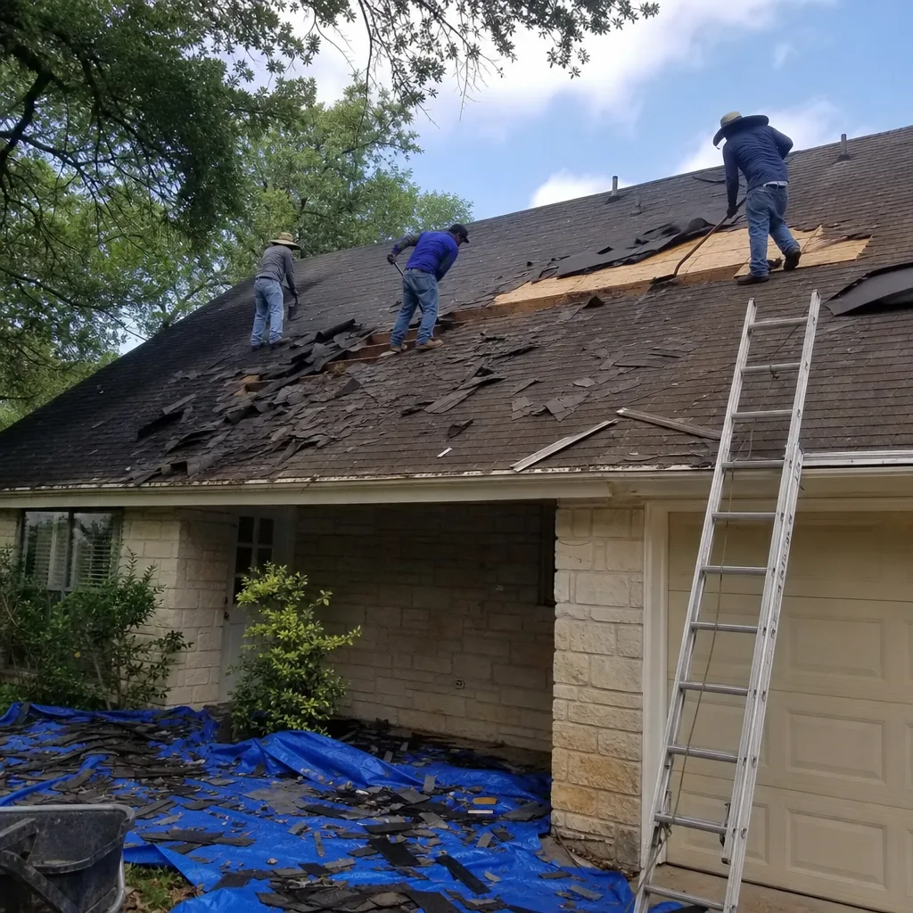 Three roofers stripping old shingles from a residential roof for replacement